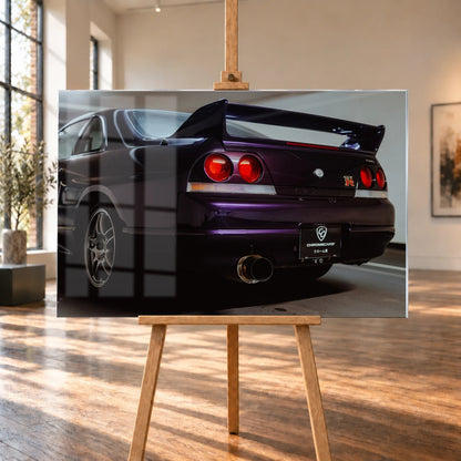 Die niedrige Heckperspektive des Nissan Skyline R33 hebt Spoiler, Rundlichter, Felgen und das große Endrohr hervor. Motiv „Skyline Drive“ als Acrylglas-Wandbild, auf einer Holzstaffelei in einem hellen Galerieraum.