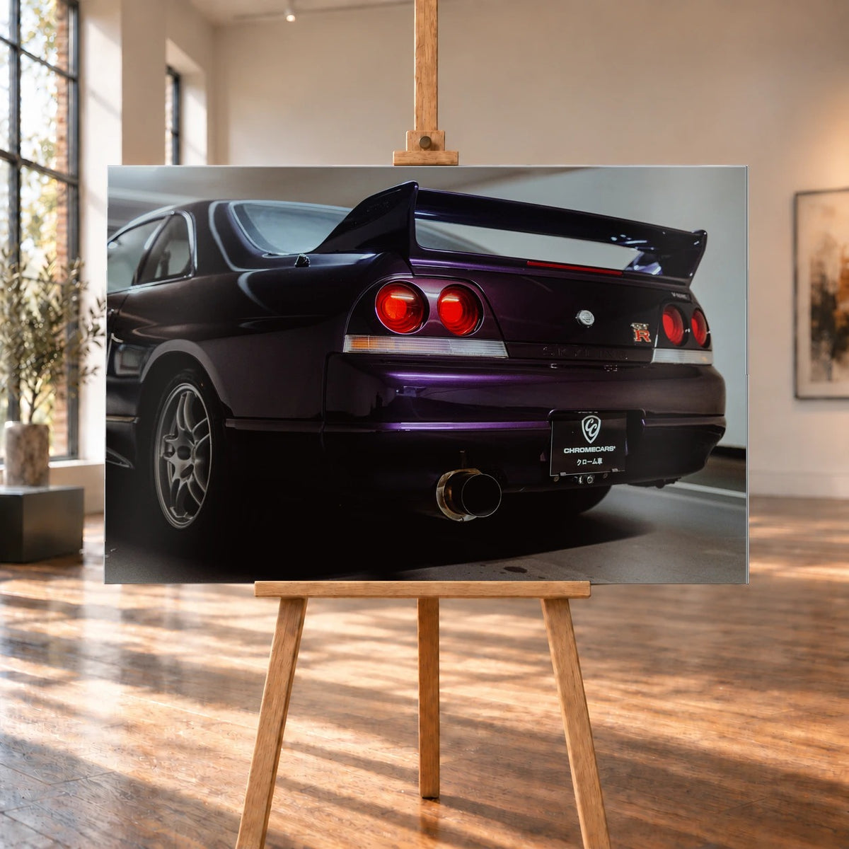 Die niedrige Heckperspektive des Nissan Skyline R33 hebt Spoiler, Rundlichter, Felgen und das große Endrohr hervor. Motiv „Skyline Drive“ als Alu gebürstet-Wandbild, auf einer Holzstaffelei in einem hellen Galerieraum.