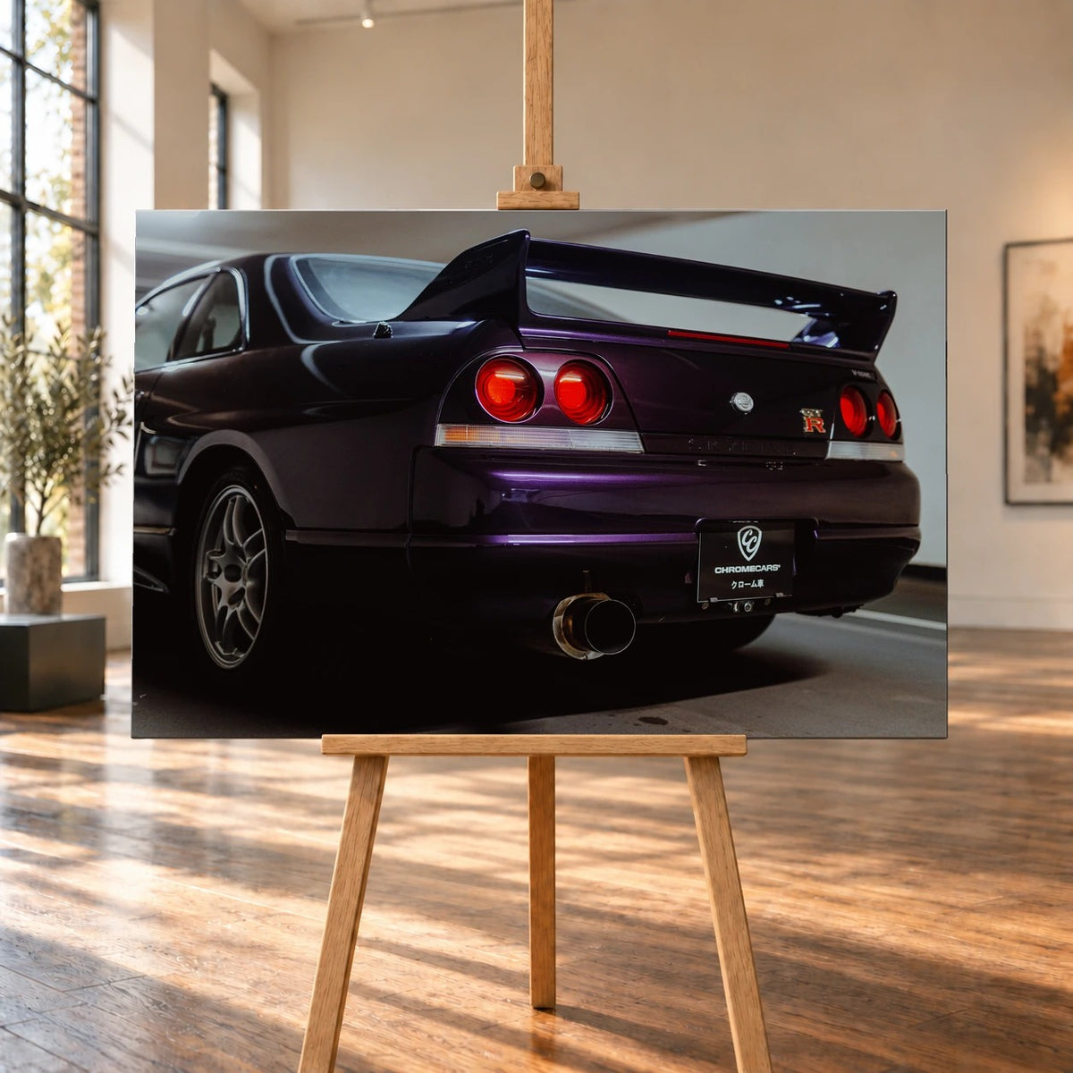 Die niedrige Heckperspektive des Nissan Skyline R33 hebt Spoiler, Rundlichter, Felgen und das große Endrohr hervor. Motiv „Skyline Drive“ als Leinwand-Wandbild, auf einer Holzstaffelei in einem hellen Galerieraum.