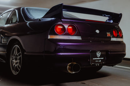 Die niedrige Heckperspektive des Nissan Skyline R33 hebt Spoiler, Rundlichter, Felgen und das große Endrohr hervor. Originalmotiv „Skyline Drive“ im Querformat.