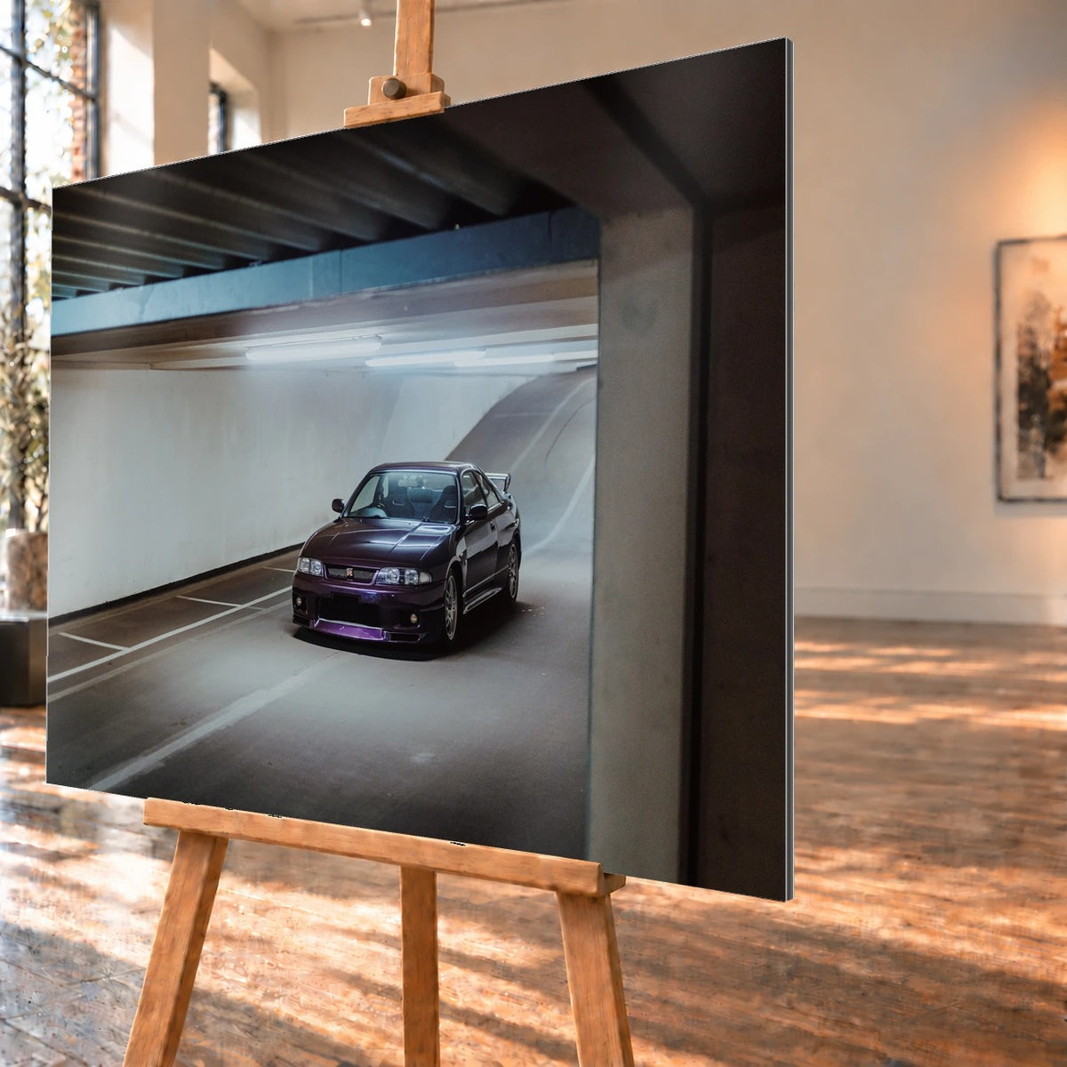 Der Nissan Skyline R33 ist schräg von vorn zwischen Betonstützen aufgenommen; violette Lackreflexe und kühles Deckenlicht bestimmen die Szene. Motiv „Skyline Motion“ als Alu gebürstet-Wandbild, schräg von der Seite auf einer Holzstaffelei.