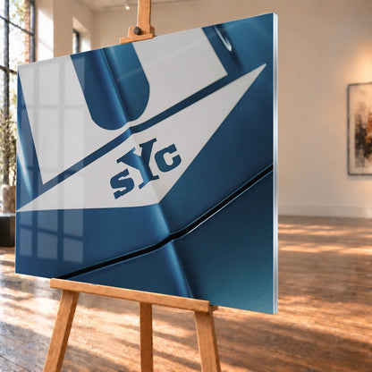 Die Nahaufnahme zeigt weiße Haubenstreifen und großen SYC-Schriftzug auf dem blauen Camaro Yenko. Motiv „Urban Light 2“ als Acrylglas-Wandbild, schräg von der Seite auf einer Holzstaffelei.
