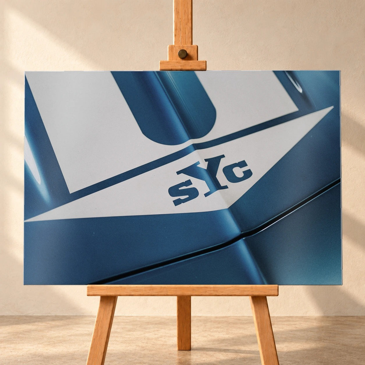 Die Nahaufnahme zeigt weiße Haubenstreifen und großen SYC-Schriftzug auf dem blauen Camaro Yenko. Motiv „Urban Light 2“ als Alu gebürstet-Wandbild, frontal auf einer Holzstaffelei.