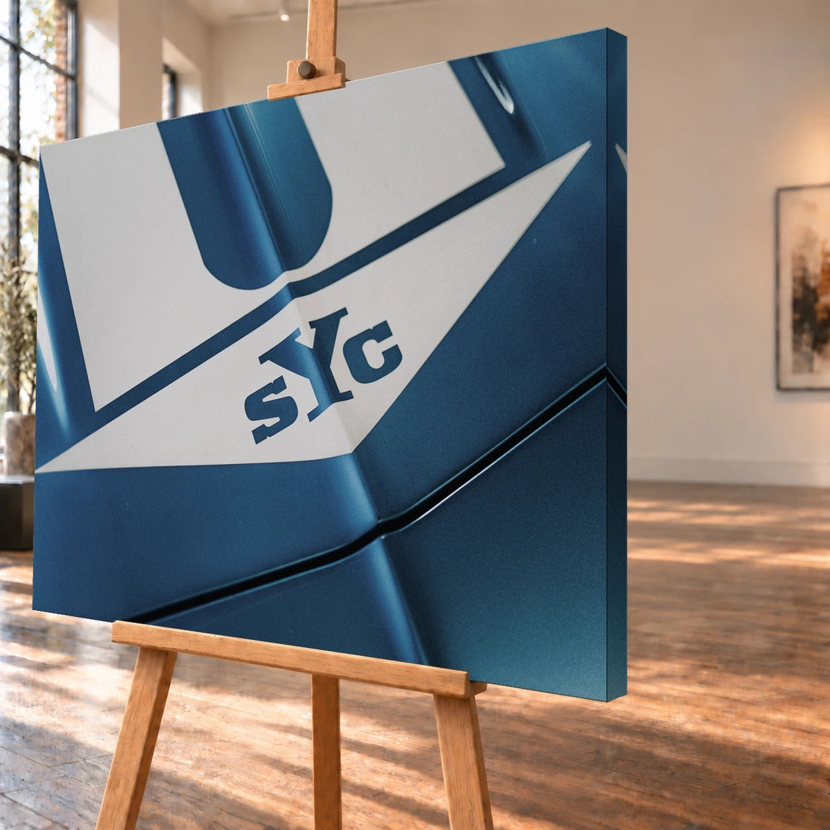 Die Nahaufnahme zeigt weiße Haubenstreifen und großen SYC-Schriftzug auf dem blauen Camaro Yenko. Motiv „Urban Light 2“ als Leinwand-Wandbild, schräg von der Seite auf einer Holzstaffelei.
