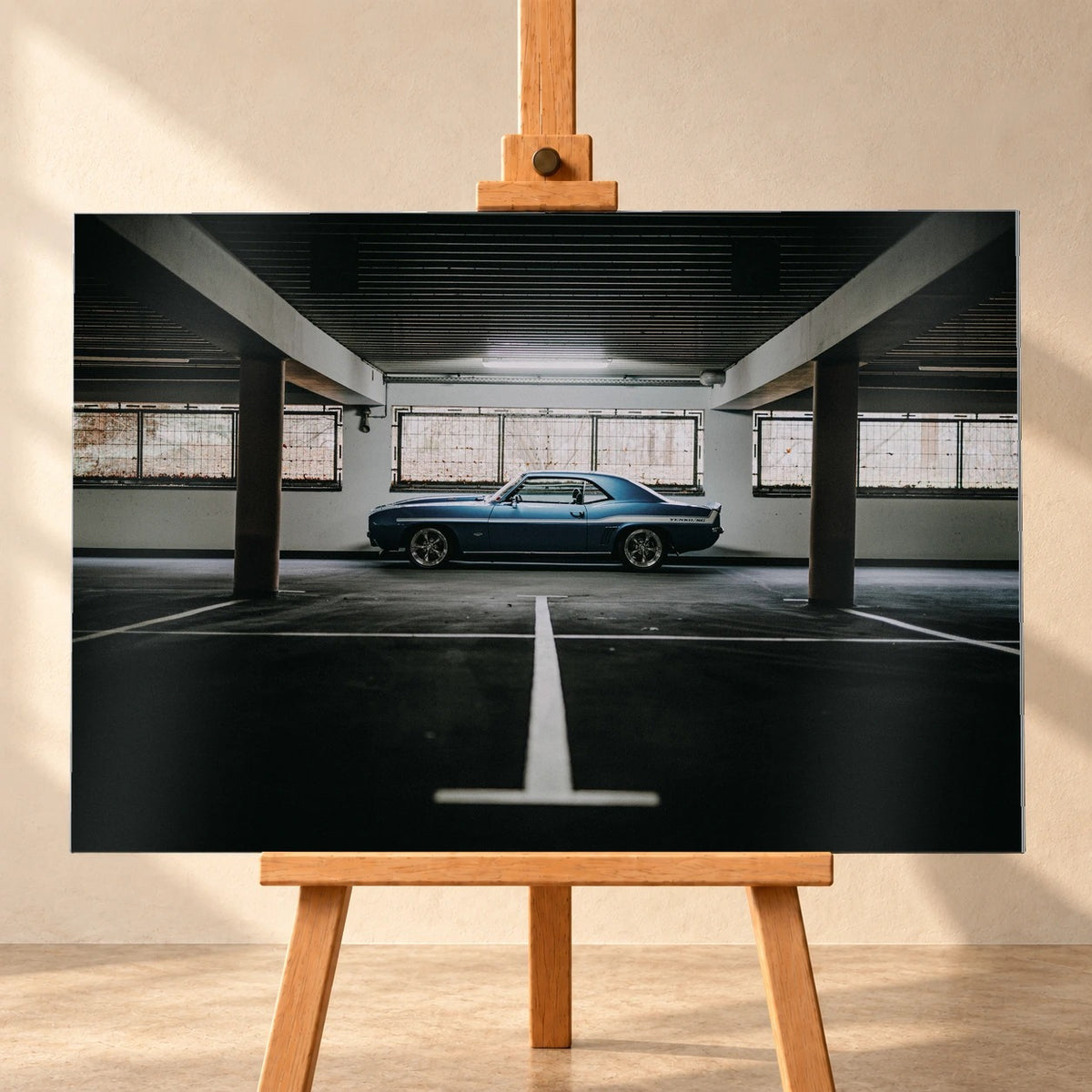 Der Camaro Yenko steht klein im Seitenprofil in einer großen, dunklen Industriehalle; helle Bodenmarkierung und Fensterlicht rahmen ihn ein. Motiv „Road Line“ als Alu gebürstet-Wandbild, frontal auf einer Holzstaffelei.