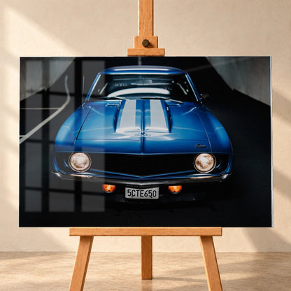 Der Camaro Yenko ist frontal und symmetrisch aufgenommen; blaue Haube, weiße Doppelstreifen und runde Scheinwerfer stehen im Mittelpunkt. Motiv „Silver Horizon 2“ als Acrylglas-Wandbild, frontal auf einer Holzstaffelei.