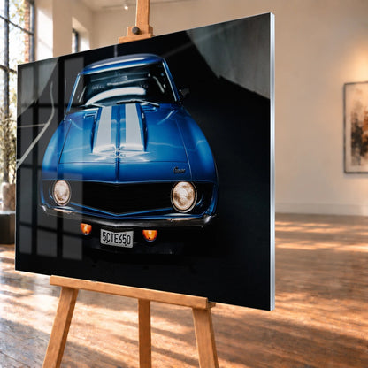 Der Camaro Yenko ist frontal und symmetrisch aufgenommen; blaue Haube, weiße Doppelstreifen und runde Scheinwerfer stehen im Mittelpunkt. Motiv „Silver Horizon 2“ als Acrylglas-Wandbild, schräg von der Seite auf einer Holzstaffelei.
