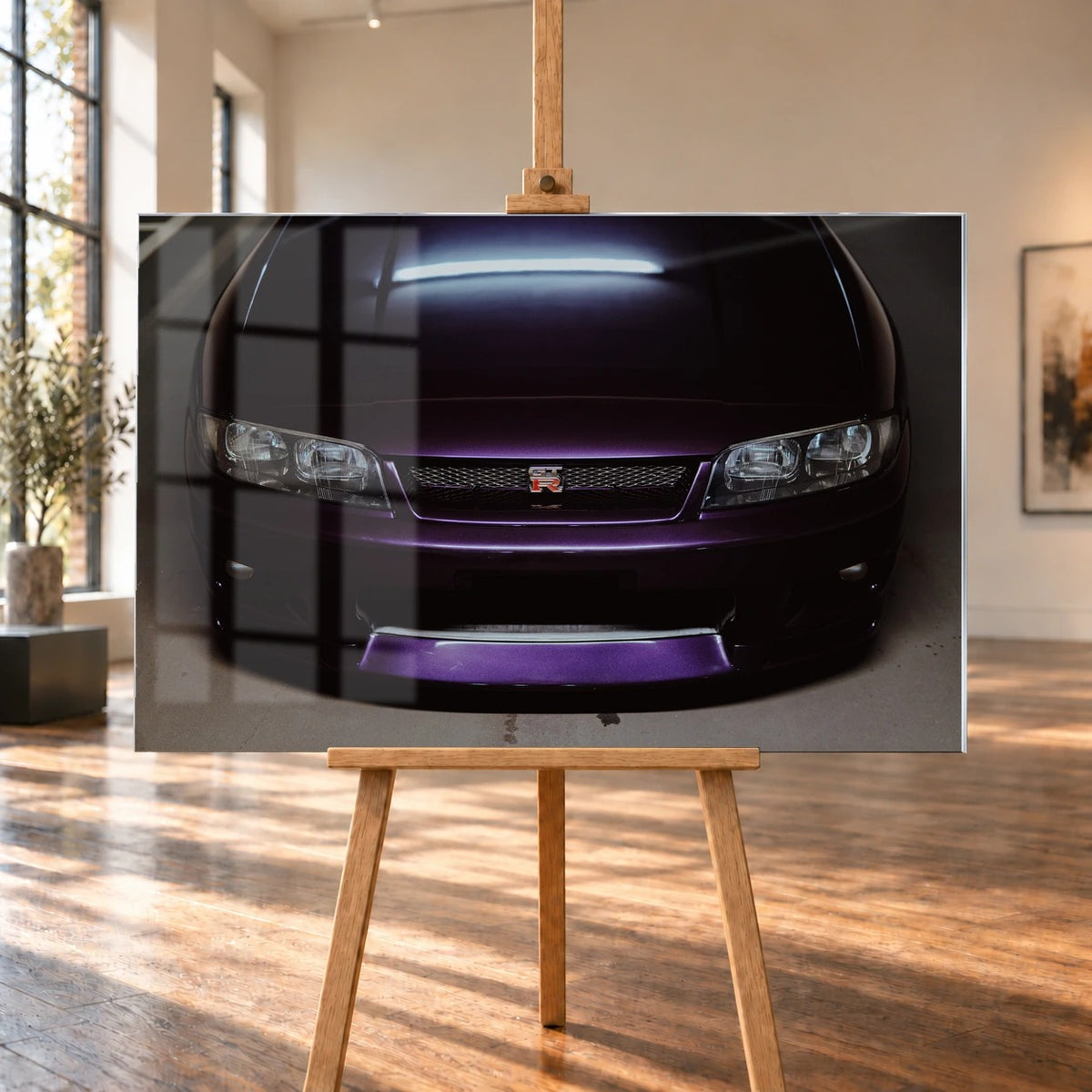 Eine enge Frontalansicht zeigt Grill, GT-R-Emblem und den violetten Frontsplitter des Nissan Skyline R33 vor dunklem Parkhausboden. Motiv „Midnight Rhythm“ als Acrylglas-Wandbild, auf einer Holzstaffelei in einem hellen Galerieraum.