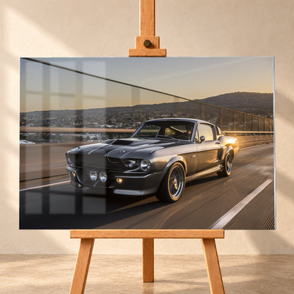 Grauer Eleanor-Sportwagen fährt im Abendlicht über eine Brücke, mit Stadt und Hügeln im Hintergrund; Visualisierung als Acrylglas-Wandbild, frontal auf einer Holzstaffelei.