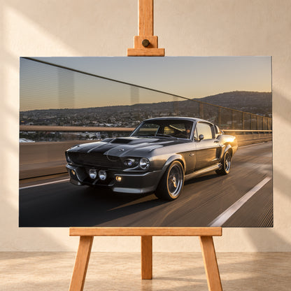 Grauer Eleanor-Sportwagen fährt im Abendlicht über eine Brücke, mit Stadt und Hügeln im Hintergrund; Visualisierung als Leinwand-Wandbild, frontal auf einer Holzstaffelei.