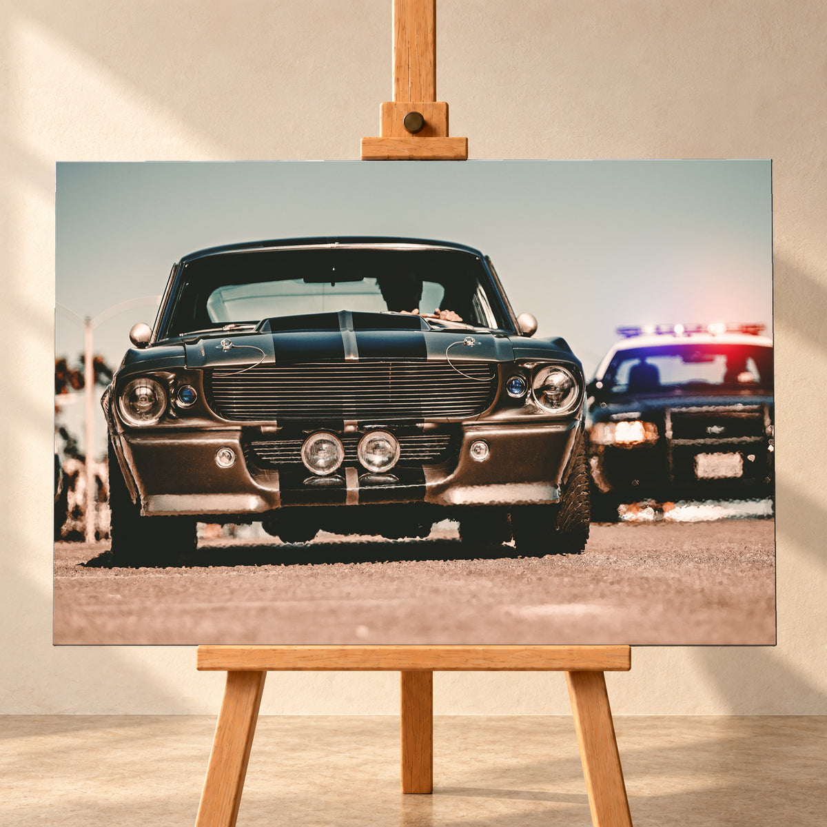Dunkler Eleanor Ford Mustang Shelby GT500 in tiefer Frontalansicht auf heller Fahrbahn, mit dunklen Längsstreifen, Motorhaubenaufsatz, Rundscheinwerfern und zwei Zusatzleuchten. Rechts dahinter steht unscharf ein dunkles Fahrzeug mit rot-blauer Lichtleiste; Visualisierung als Leinwand-Wandbild, frontal auf einer Holzstaffelei.