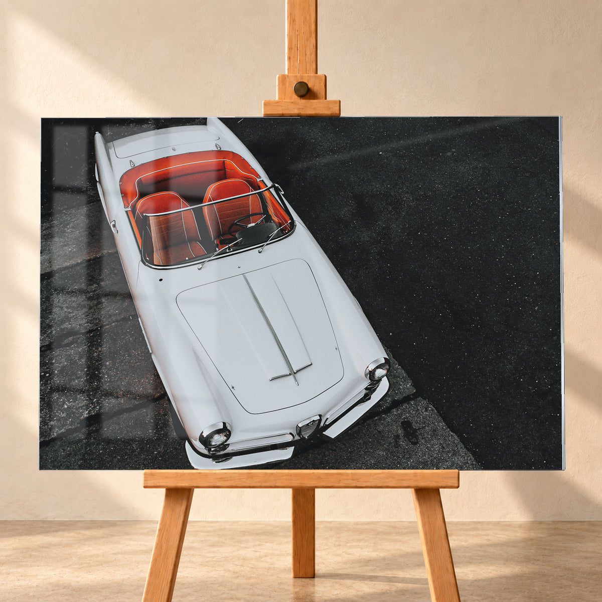Heller Alfa Romeo 2000 Touring Spider in steiler Aufsicht, diagonal auf dunklem Asphalt; sichtbar sind das offene rot-orange Cockpit, Lenkrad, Windschutzscheibe, lange Motorhaube, runde Frontleuchten und Chromdetails; Visualisierung als Acrylglas-Wandbild, frontal auf einer Holzstaffelei.