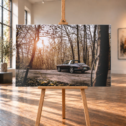 Dunkler 1967 Porsche 911 S Softwindow in seitlicher Heckansicht auf einer unbefestigten Fläche im Wald. Die offene Dachpartie und die helle Bügelzone sind sichtbar, während tiefes Sonnenlicht links durch hohe, spärlich belaubte Bäume fällt; Visualisierung als Alu gebürstet-Wandbild, auf einer Holzstaffelei in einem hellen Galerieraum.