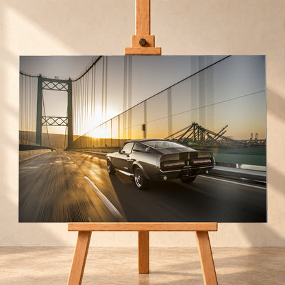 Dunkelgrauer Ford Mustang Fastback in Heck-Dreiviertelansicht auf einer Hängebrücke; goldenes Gegenlicht spiegelt sich auf der Fahrbahn, rechts sind Wasser und Hafenkräne zu sehen; Visualisierung als Alu gebürstet-Wandbild, frontal auf einer Holzstaffelei.