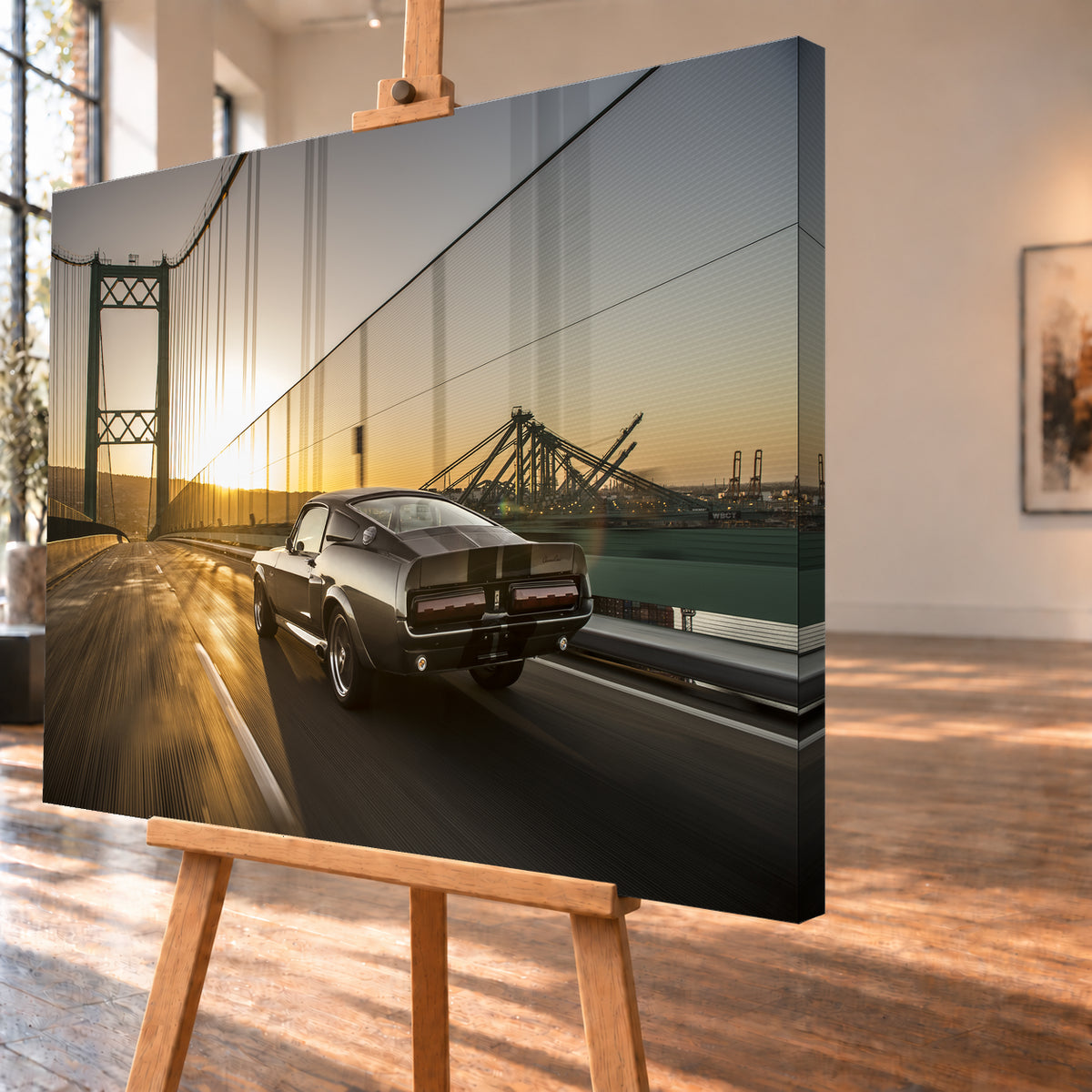 Dunkelgrauer Ford Mustang Fastback in Heck-Dreiviertelansicht auf einer Hängebrücke; goldenes Gegenlicht spiegelt sich auf der Fahrbahn, rechts sind Wasser und Hafenkräne zu sehen; Visualisierung als Leinwand-Wandbild, schräg von der Seite auf einer Holzstaffelei.