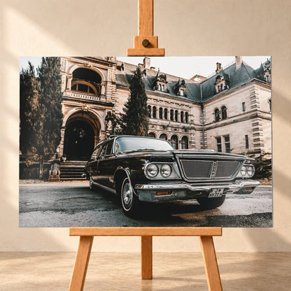 Dunkler Chrysler New Yorker Town & Country in niedriger Front-Dreiviertelansicht vor einem großen historischen Steingebäude mit Rundbögen; warmes Tageslicht spiegelt sich in Chromfront und Lack; Visualisierung als Alu gebürstet-Wandbild, frontal auf einer Holzstaffelei.
