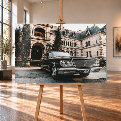 Dunkler Chrysler New Yorker Town & Country in niedriger Front-Dreiviertelansicht vor einem großen historischen Steingebäude mit Rundbögen; warmes Tageslicht spiegelt sich in Chromfront und Lack; Visualisierung als Alu gebürstet-Wandbild, auf einer Holzstaffelei in einem hellen Galerieraum.