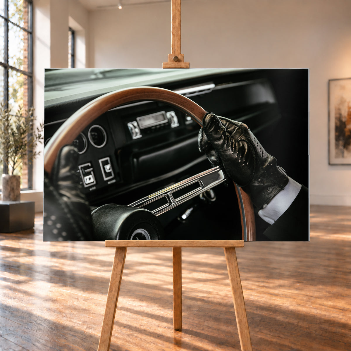 Nahaufnahme eines dunklen Fahrzeugcockpits: Eine Hand in schwarzem, perforiertem Handschuh greift ein braunes, holzfarbenes Lenkrad. Rundinstrumente, Radio und Armaturenbrett liegen unscharf im Hintergrund; seitliches Licht hebt Handschuh, Lenkradkranz und metallisch glänzende Speiche hervor; Visualisierung als Alu gebürstet-Wandbild, auf einer Holzstaffelei in einem hellen Galerieraum.
