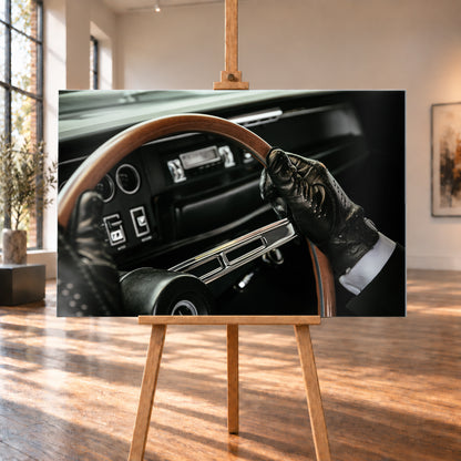 Nahaufnahme eines dunklen Fahrzeugcockpits: Eine Hand in schwarzem, perforiertem Handschuh greift ein braunes, holzfarbenes Lenkrad. Rundinstrumente, Radio und Armaturenbrett liegen unscharf im Hintergrund; seitliches Licht hebt Handschuh, Lenkradkranz und metallisch glänzende Speiche hervor; Visualisierung als Alu gebürstet-Wandbild, auf einer Holzstaffelei in einem hellen Galerieraum.