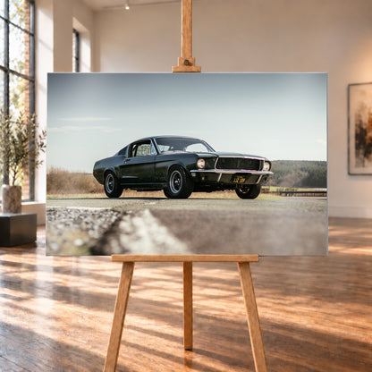 Dunkelgrüner Ford Mustang in niedriger Dreiviertelansicht von vorn auf Asphalt; dahinter offene Felder, ein bewaldeter Horizont und heller Himmel bei Tageslicht; Visualisierung als Alu gebürstet-Wandbild, auf einer Holzstaffelei in einem hellen Galerieraum.