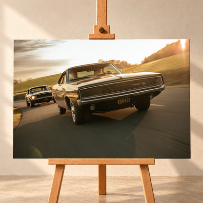 Dunkel erscheinender Dodge Charger R/T aus tiefer Frontperspektive auf einer kurvigen Landstraße; dahinter folgt ein weiteres dunkles Coupé. Goldenes Gegenlicht, grüne Hügel und starke Bewegungsunschärfe prägen die Fahrszene; Visualisierung als Leinwand-Wandbild, frontal auf einer Holzstaffelei.