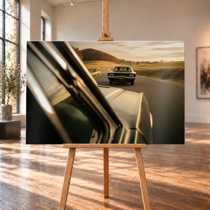 Dunkler Dodge Charger 440 R/T von hinten auf einer kurvigen Landstraße im goldenen Abendlicht, fotografiert aus einem zweiten fahrenden Auto; rote Rückleuchten, Wiesen und Bewegungsunschärfe; Visualisierung als Alu gebürstet-Wandbild, auf einer Holzstaffelei in einem hellen Galerieraum.