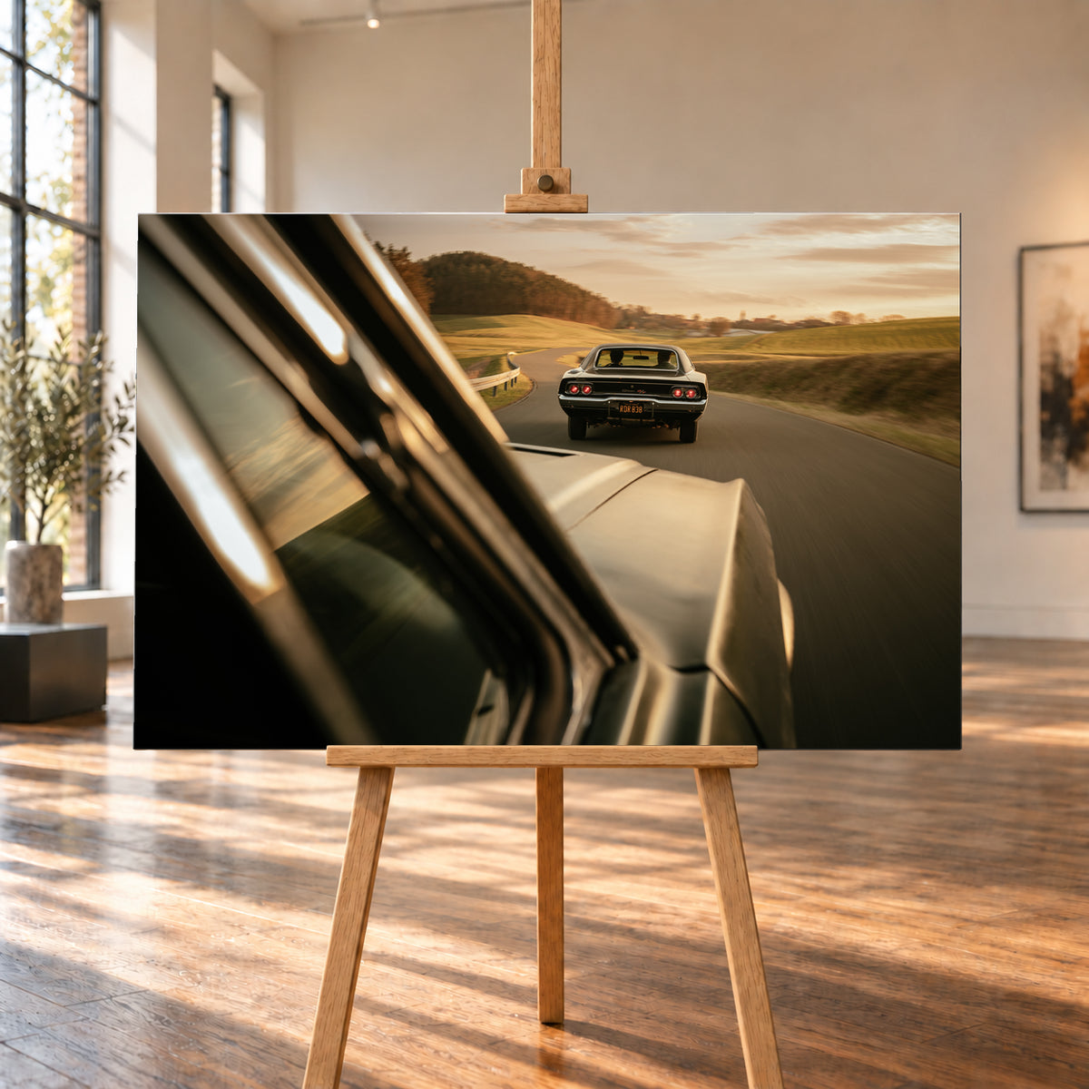 Dunkler Dodge Charger 440 R/T von hinten auf einer kurvigen Landstraße im goldenen Abendlicht, fotografiert aus einem zweiten fahrenden Auto; rote Rückleuchten, Wiesen und Bewegungsunschärfe; Visualisierung als Leinwand-Wandbild, auf einer Holzstaffelei in einem hellen Galerieraum.
