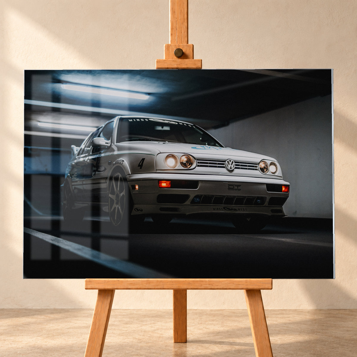 Hellsilberner Volkswagen Jetta mit eingeschalteten Scheinwerfern, grafischen Beklebungen und Nummer 4 in niedriger Front-Dreiviertelansicht auf einer Rampe in einer dunkel und blau beleuchteten Parkgarage; Visualisierung als Acrylglas-Wandbild, frontal auf einer Holzstaffelei.