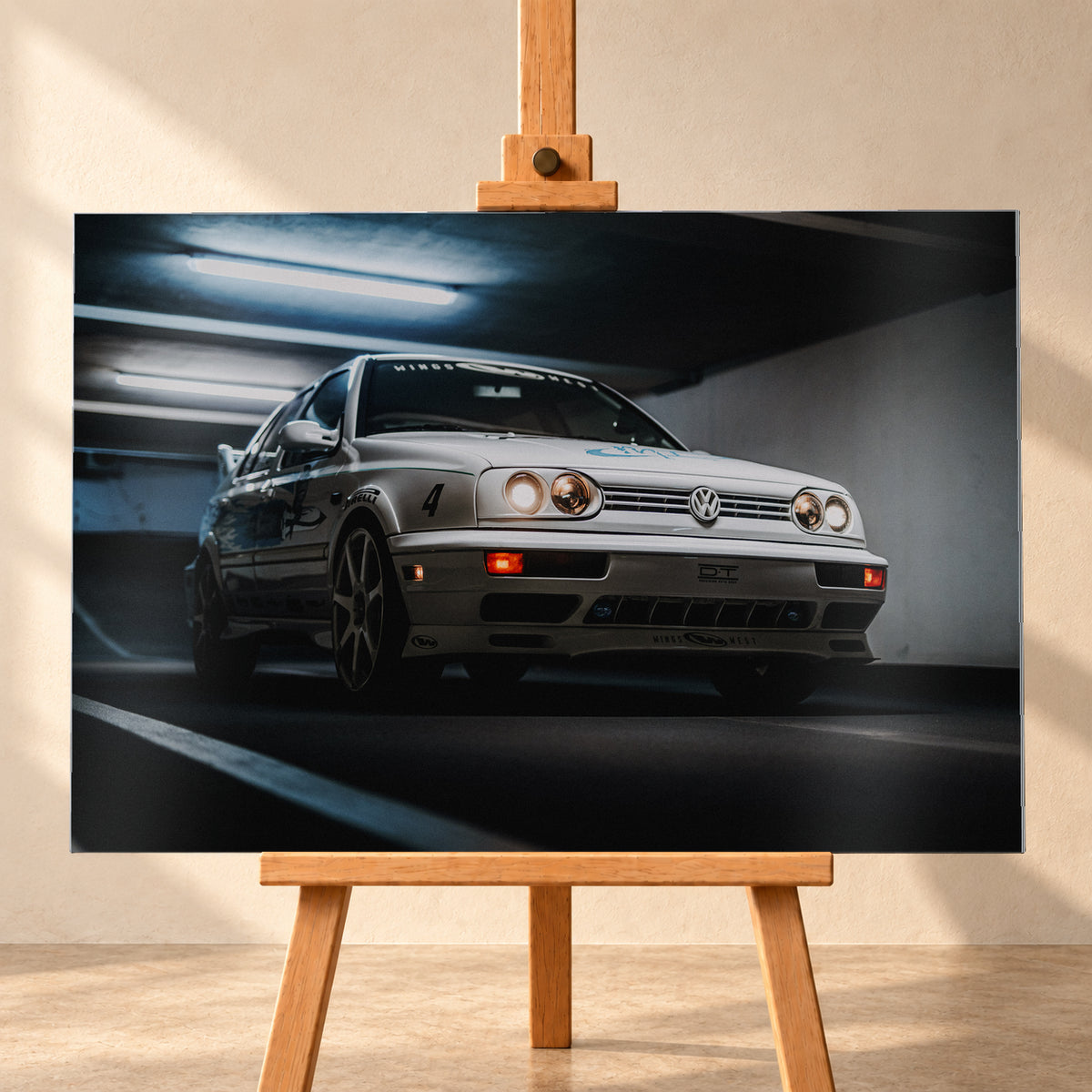 Hellsilberner Volkswagen Jetta mit eingeschalteten Scheinwerfern, grafischen Beklebungen und Nummer 4 in niedriger Front-Dreiviertelansicht auf einer Rampe in einer dunkel und blau beleuchteten Parkgarage; Visualisierung als Alu gebürstet-Wandbild, frontal auf einer Holzstaffelei.