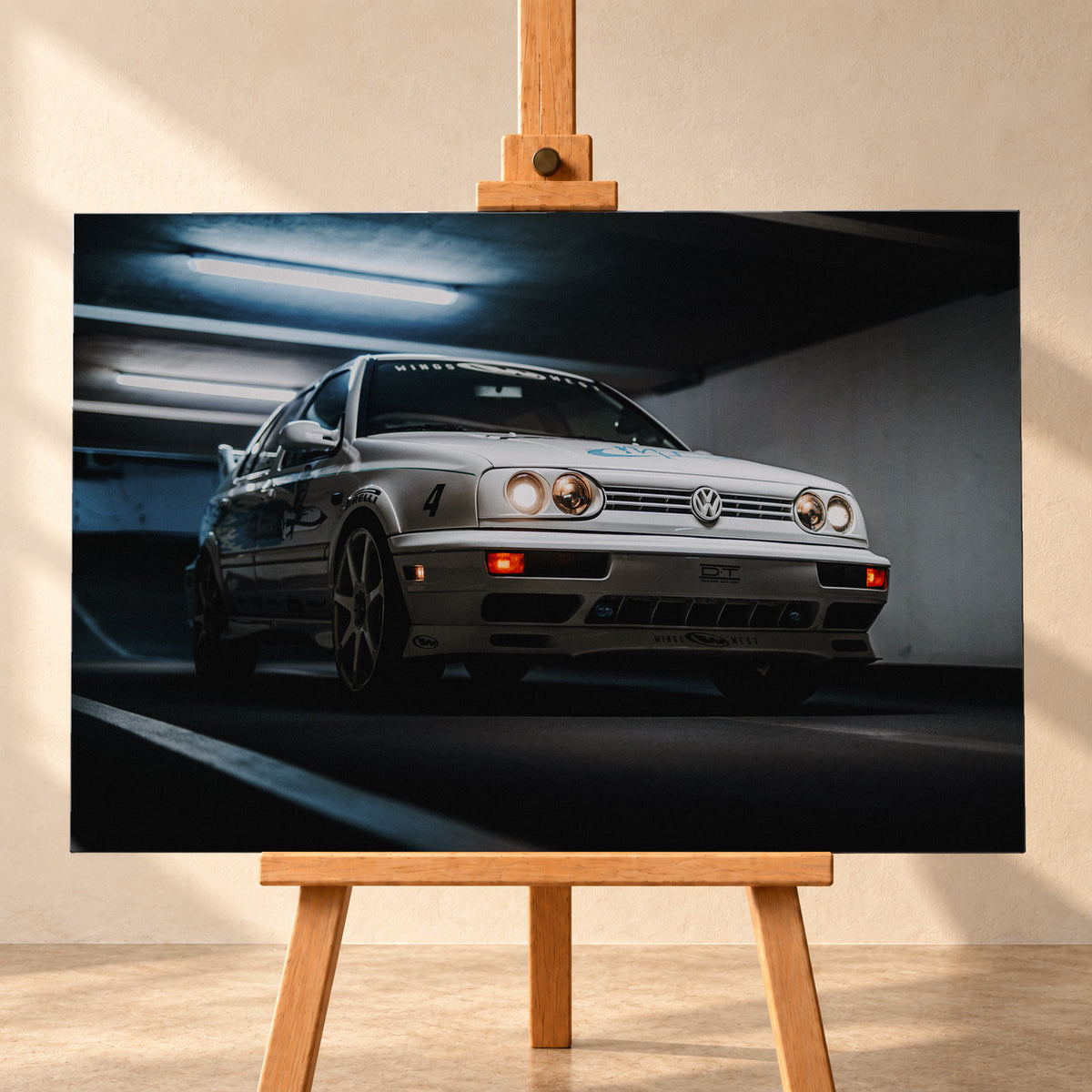 Hellsilberner Volkswagen Jetta mit eingeschalteten Scheinwerfern, grafischen Beklebungen und Nummer 4 in niedriger Front-Dreiviertelansicht auf einer Rampe in einer dunkel und blau beleuchteten Parkgarage; Visualisierung als Leinwand-Wandbild, frontal auf einer Holzstaffelei.