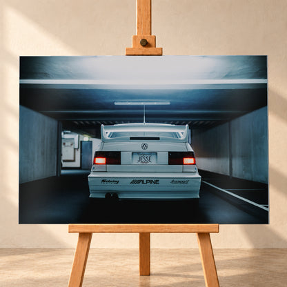 Weißer Volkswagen Jetta in symmetrischer Heckansicht in einer dunklen Betongarage, mit großem Heckflügel, roten Rücklichtern, sichtbaren Aufklebern und kühlem blau-grauem Licht; Visualisierung als Alu gebürstet-Wandbild, frontal auf einer Holzstaffelei.