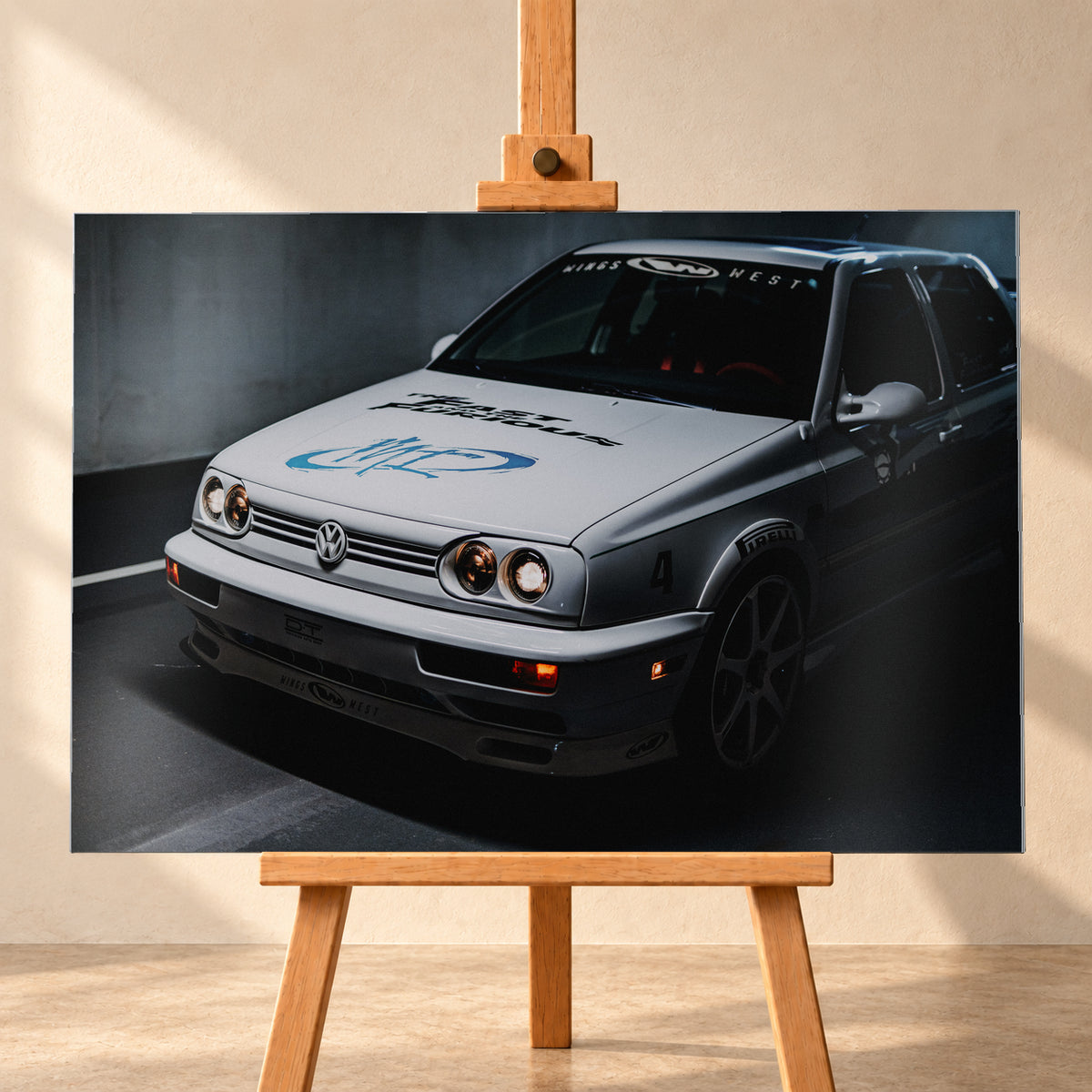 Heller Volkswagen Jetta in frontaler Dreiviertelansicht vor dunklem Hintergrund, mit eingeschalteten runden Frontscheinwerfern, orangefarbenen Leuchten, schwarzen und blauen Grafiken auf der Motorhaube sowie sichtbaren Aufklebern an Scheibe und Karosserie; Visualisierung als Alu gebürstet-Wandbild, frontal auf einer Holzstaffelei.
