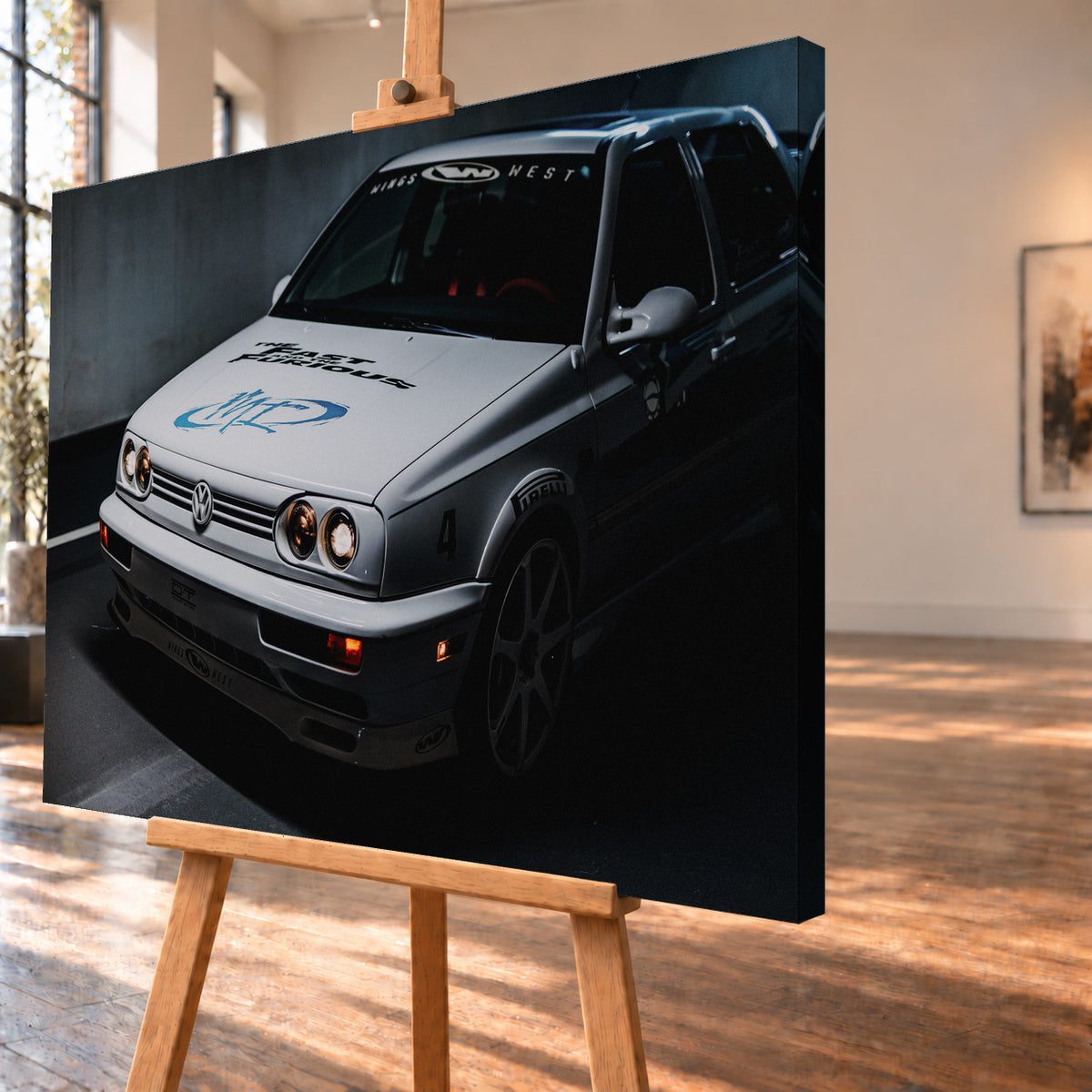 Heller Volkswagen Jetta in frontaler Dreiviertelansicht vor dunklem Hintergrund, mit eingeschalteten runden Frontscheinwerfern, orangefarbenen Leuchten, schwarzen und blauen Grafiken auf der Motorhaube sowie sichtbaren Aufklebern an Scheibe und Karosserie; Visualisierung als Leinwand-Wandbild, schräg von der Seite auf einer Holzstaffelei.