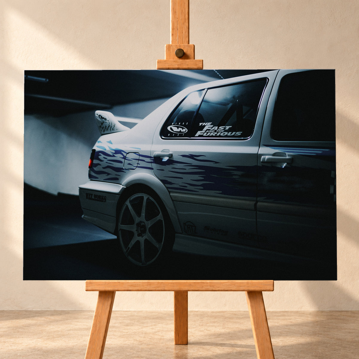 Nahaufnahme der hinteren Seitenpartie eines hellen VW Jetta mit blau-violetter Flammengrafik, großem Rad und Heckflügel. Im dunklen Seitenfenster steht „The Fast and the Furious“; kühles Licht fällt auf Wand und Boden; Visualisierung als Leinwand-Wandbild, frontal auf einer Holzstaffelei.