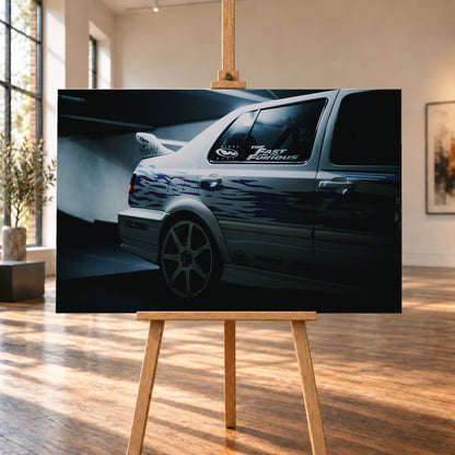 Nahaufnahme der hinteren Seitenpartie eines hellen VW Jetta mit blau-violetter Flammengrafik, großem Rad und Heckflügel. Im dunklen Seitenfenster steht „The Fast and the Furious“; kühles Licht fällt auf Wand und Boden; Visualisierung als Leinwand-Wandbild, auf einer Holzstaffelei in einem hellen Galerieraum.
