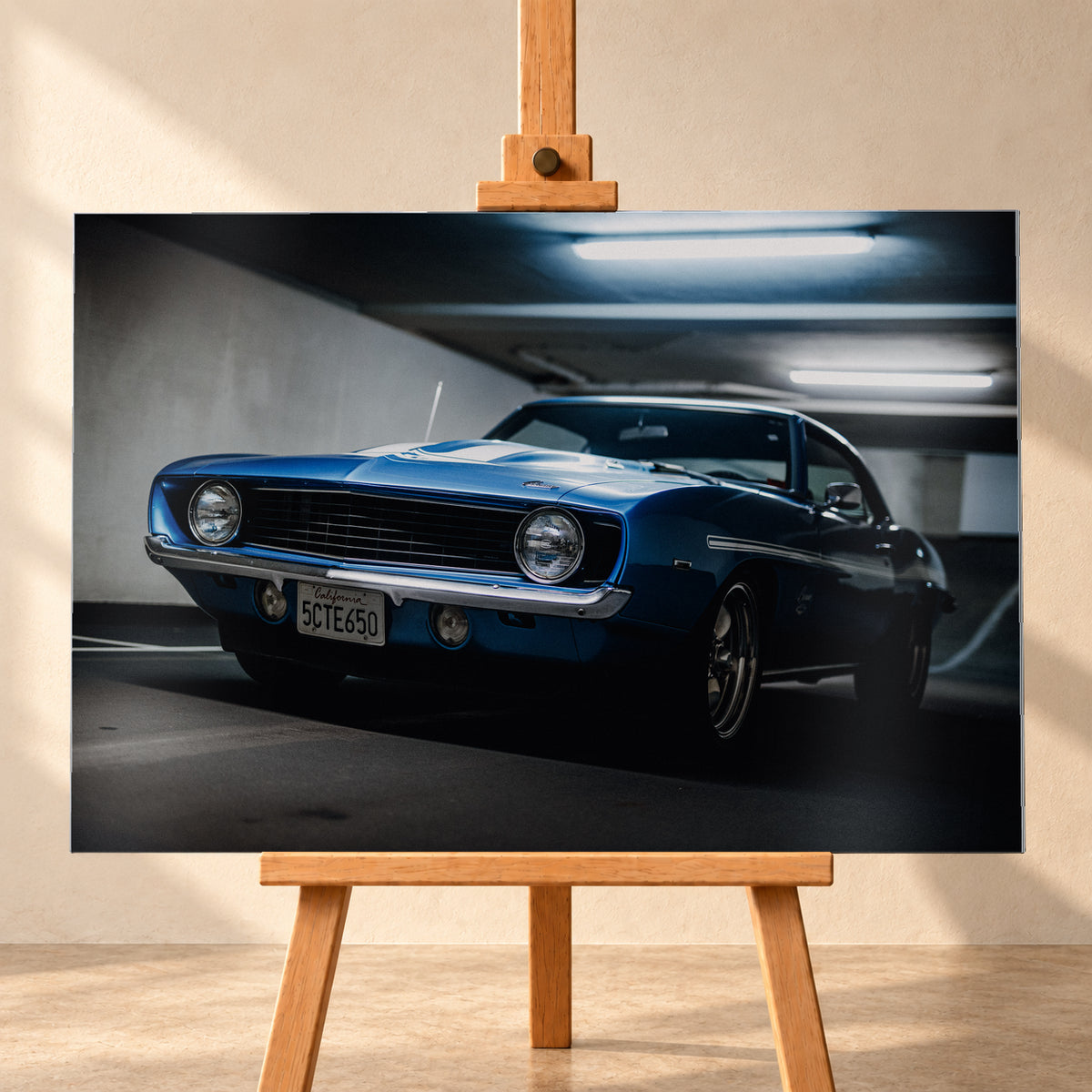 Blauer Yenko Camaro in tiefer Front-Dreiviertelansicht in einer dunklen Parkgarage; sichtbar sind runde Scheinwerfer, schwarzer Kühlergrill, Chromstoßstange, helle Streifen und leuchtende Deckenröhren; Visualisierung als Alu gebürstet-Wandbild, frontal auf einer Holzstaffelei.