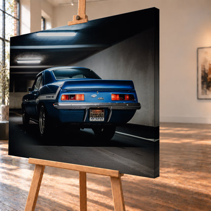 Blauer Chevrolet Camaro Yenko in tiefer Heck-Dreiviertelansicht in einer dunklen Parkgarage; rote Rücklichter, Heckspoiler, YENKO/SC-Seitenstreifen und kühle Deckenleuchten sind sichtbar; Visualisierung als Leinwand-Wandbild, schräg von der Seite auf einer Holzstaffelei.