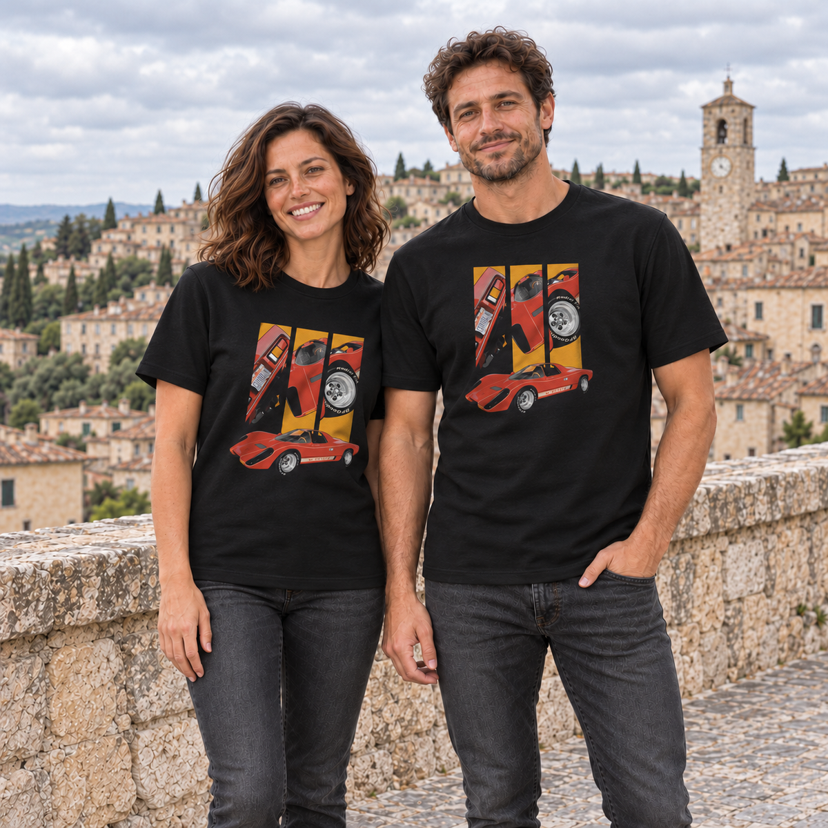 Frau und Mann nebeneinander in schwarzen T-Shirts; beide zeigen das Coyote-X-Motiv vorn vor der Altstadtmauer.