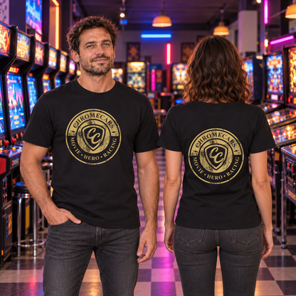 Zwei Personen in schwarzen T-Shirts stehen zwischen Spielhallenautomaten: der Mann frontal mit einer Hand in der Hosentasche, die Frau rückwärts; goldfarbenes Logo bei ihm vorne, bei ihr hinten.
