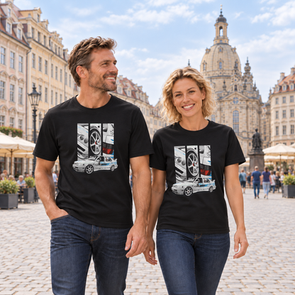 Mann und Frau in schwarzen T-Shirts mit Jetta-Motiven vorn, auf einem gepflasterten Stadtplatz vor historischen Gebäuden und einer Kuppelkirche.