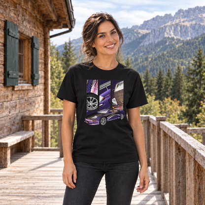Frau von vorn im schwarzen T-Shirt mit Mitsu-Lila-Motiv auf der Vorderseite, auf einer Holzterrasse vor einer Berghütte und Bergen.