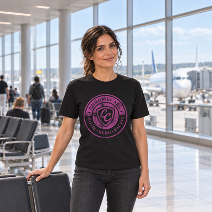 Eine Frau im schwarzen T-Shirt mit pinkem ChromeCars-Logo vorne legt eine Hand auf eine Sitzlehne und blickt zur Kamera. Hinter ihr liegen Fenster und Vorfeld des Flughafenterminals.