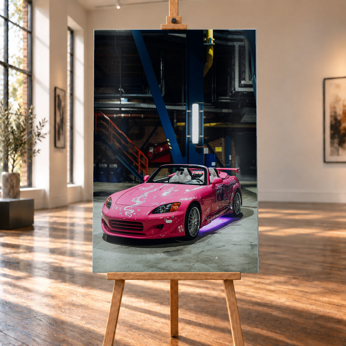 Ein Wandbild auf gebürstetem Alu im Hochformat ist auf einer Holzstaffelei in einem lichtdurchfluteten Raum mit großen Fenstern visualisiert. Das Motiv zeigt den pinken Honda S2000 aus „2 Fast 2 Furious“ mit violetter Unterbodenbeleuchtung vor dem dunklen Hintergrund einer Industriehalle.