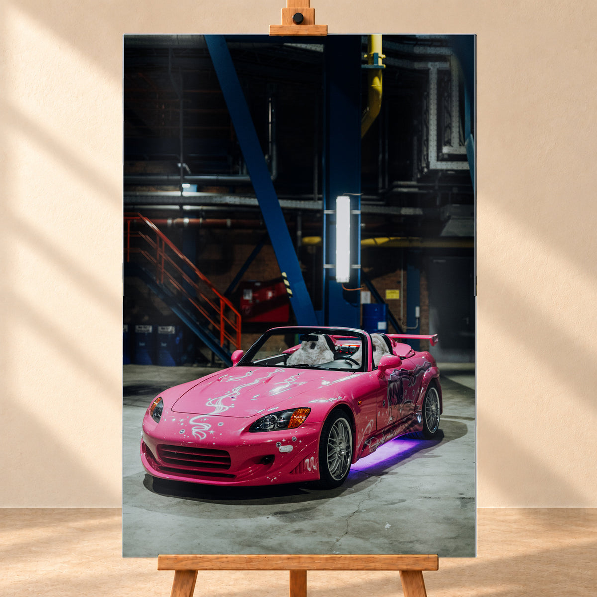 Hochformatiges Wandbild auf gebürstetem Alu als frontale Visualisierung auf einer Holzstaffelei vor heller Wand. Abgebildet ist der pinke Honda S2000 aus „2 Fast 2 Furious“ mit offenem Verdeck und violetter Unterbodenbeleuchtung in einer dunklen Industriehalle.