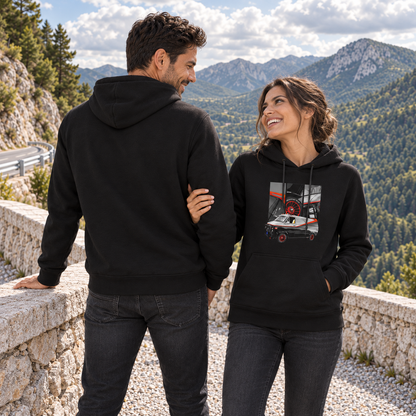 Paar in schwarzen Hoodies an der Steinmauer: Der Mann zeigt den unbedruckten Rücken, die Frau mit Vanmotiv auf der Vorderseite hält seinen Arm und schaut zu ihm auf.