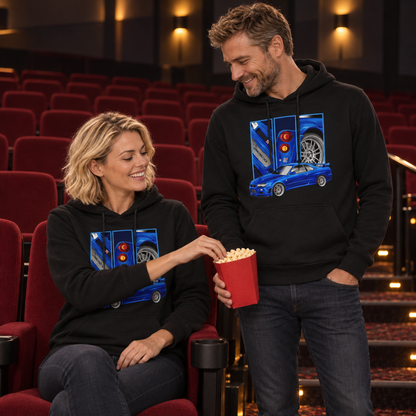 Frau sitzt im schwarzen Hoodie im Kino und greift in die Popcornschachtel eines stehenden Mannes. Beide Frontmotive sind sichtbar, ihres teilweise vom Arm verdeckt.