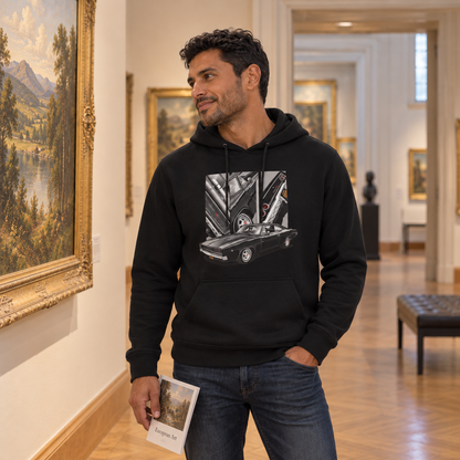 Mann im schwarzen Hoodie steht neben einem gerahmten Gemälde im Ausstellungsraum und hält ein Heft. Vorn ist ein schwarzes Coupé unter drei Detailfeldern zu sehen.