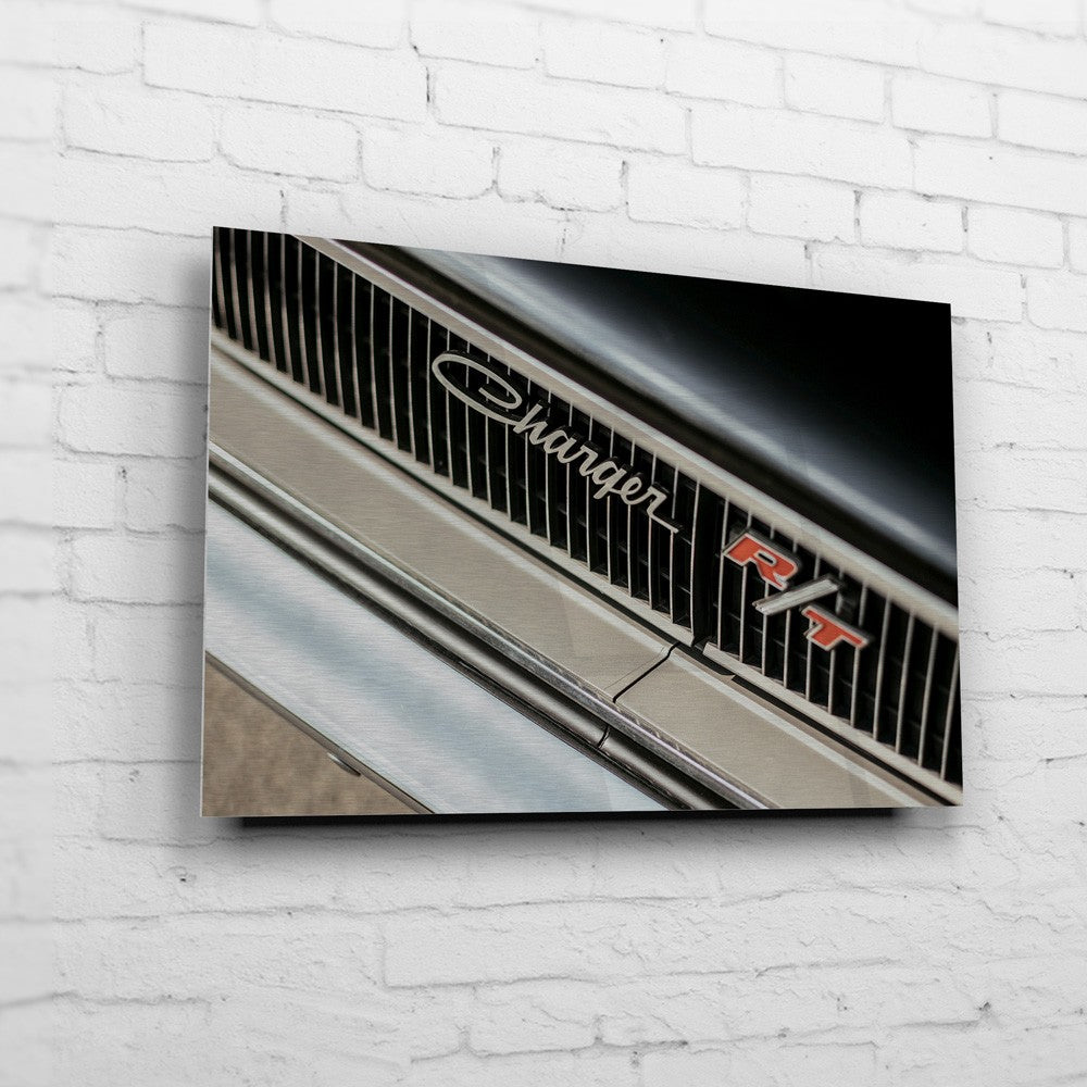 Bullitt Charger – RT Grille Detail auf gebürstetem Aluminium an weißer Ziegelwand