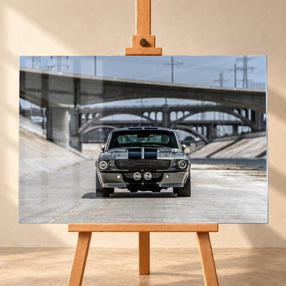 Als Acrylglas-Wandbild visualisiertes Eleanor-Motiv, frontal auf einer Holzstaffelei vor heller Wand präsentiert. Der silbergraue Ford Mustang Shelby GT500 mit schwarzen Doppelstreifen steht mittig in einem Betonkanal; dahinter liegen mehrere Brücken.