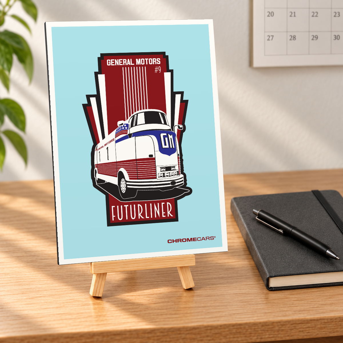 Mockup einer kleinen Alu-Dibond-Bildplatte im Hochformat auf einer Holzstaffelei, nahezu frontal auf einem Holzschreibtisch betrachtet; die linke Plattenkante ist sichtbar. Das Motiv zeigt den rot-weißen GM Futurliner #9 mit blauer Frontpartie in Dreiviertelansicht auf türkisfarbenem Grund mit rot-schwarzer Grafik. Notizbuch, Stift, Wandkalender und Pflanze sind Szenerie, nicht Lieferumfang.